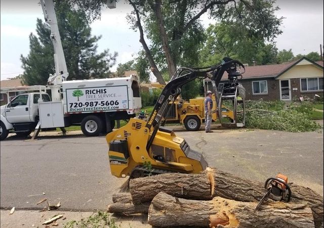 A tree chipper is sitting on a pile of logs next to a truck.